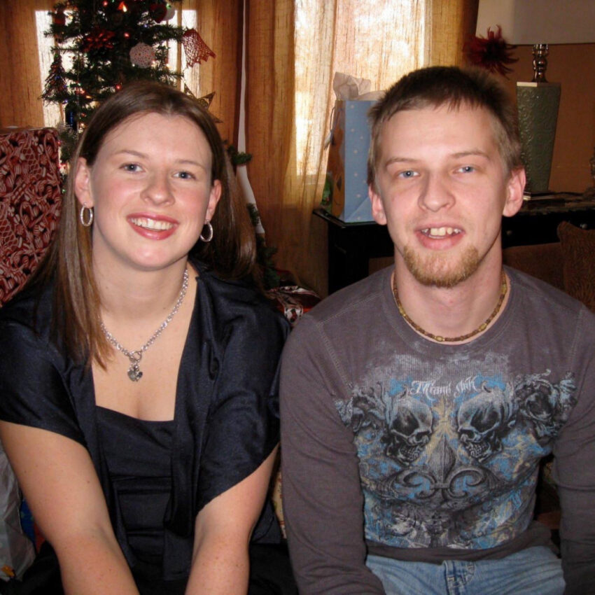 Amanda Myers and her late brother posing for a holiday photo in front of the Christmas tree.