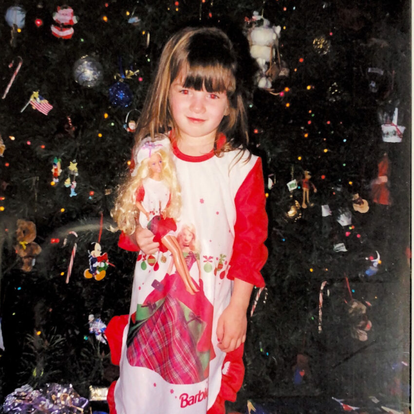 Jennifer Drake and her barbie doll in front of the tree in her holiday photo